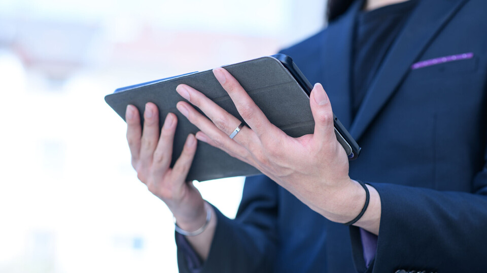 Studierender auf dem Uni Campus Eine Frau hält ein Tablet in ihren Händen.