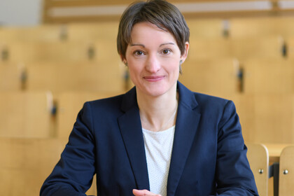 Portrait von Tabea Bucher-Koenen. Sie trägt ein weißes T-Shirt und einen dunkelblauen Blazer.