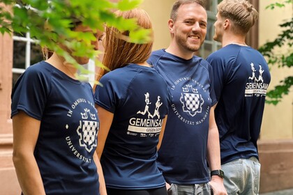 Vier Studierende stehen in einer Reihe, abwechselnd mit dem Gesicht zur Fotografin beziehungsweise abgewendet. Sie tragen das blaue Lauf-Shirt der Universität Mannheim.