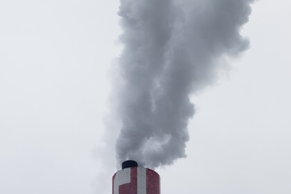 Dicker Rauch steigt aus einem Industrieschornstein in den Himmel