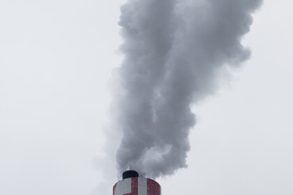 Dicker Rauch steigt aus einem Industrieschornstein in den Himmel