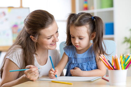 Mother looking how her child daughter drawing a picture