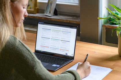 Eine Studentin arbeitet mit ihrem Laptop und einem Blatt Papier.