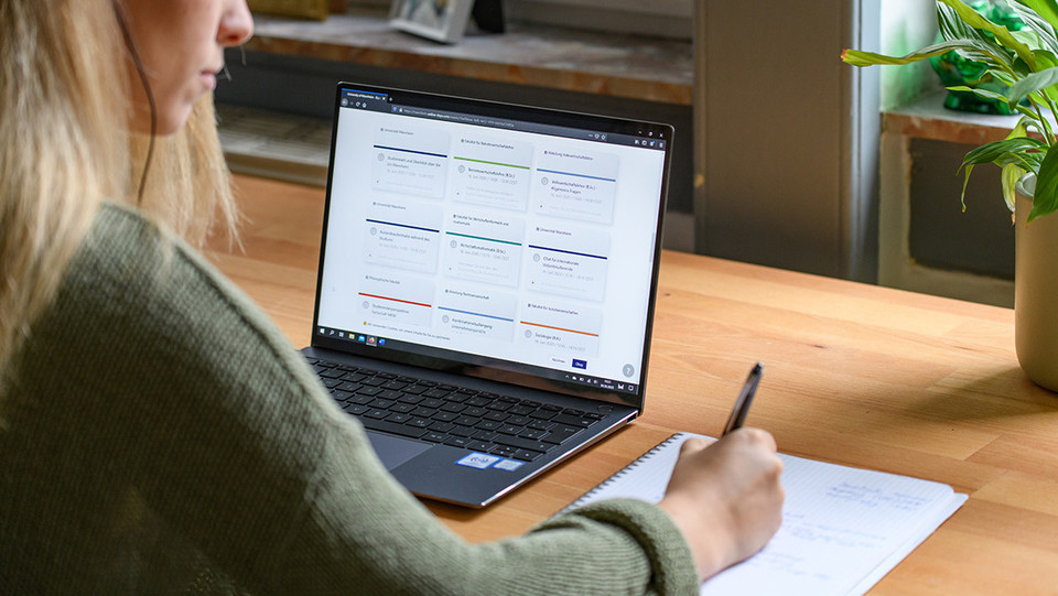 Eine Studentin arbeitet mit ihrem Laptop und einem Blatt Papier.