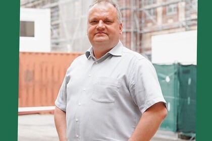 Matthias Heitz hat kurze graue Haare. Er trägt ein hellgraues Hemd und eine schwarze Hose.
