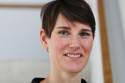 Portrait von Annelies Blom. Sie trägt einen blau-schwarzen Pullover und lächelt.
