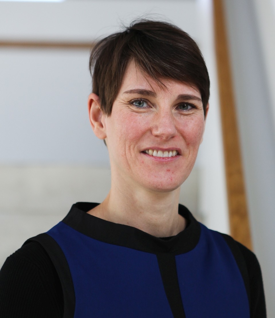 Portrait von Annelies Blom. Sie trägt einen blau-schwarzen Pullover und lächelt.
