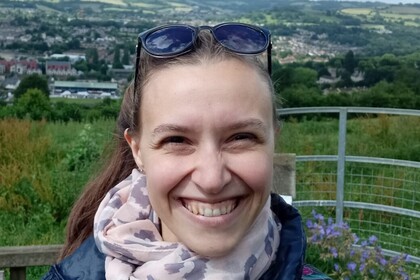 Vera Vogel im Freien. Sie trägt eine Sonnenbrille auf dem Kopf und einen gemusterten Schal, dazu eine Jeansjacke.