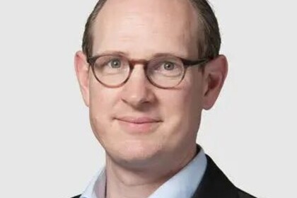 Portrait von Oliver Spalt. Er trägt eine Brille, ein hellblaues Hemd und ein dunkelgraues Sakko.