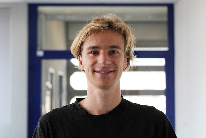 Portrait von Oliver Rittman. Erträgt ein schwarzes T-Shirt und hat blonde Haare. 