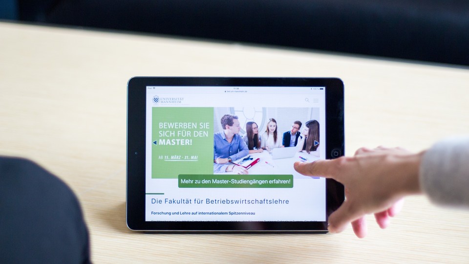 Zoom Tablet Finger zeigt auf Tablet, auf dem steht: Bewerben Sie sich für den Master! Ab 15. März - 31. Mai
