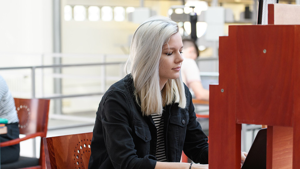 Eine Studentin arbeitet in der A3-Bibliothek an ihrem Laptop. 