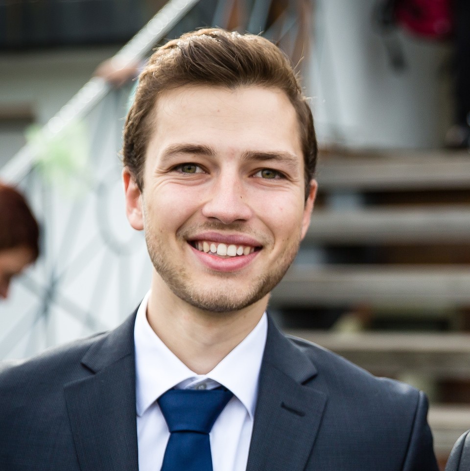 Stefan Fraunholz hat kurze braune Haare. Er trägt ein helles Hemd, eine dunkelblaue Krawatte und einen dunklen Anzug darüber