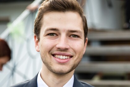 Stefan Fraunholz hat kurze braune Haare. Er trägt ein helles Hemd, eine dunkelblaue Krawatte und einen dunklen Anzug darüber