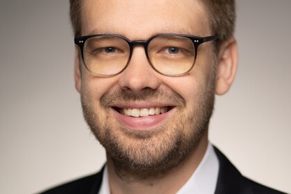 Prof. Dr. Marc Lerchenmüller hat blonde kurze Haare und einen Bart. Er trägt ein dunkles Jacket und ein weißes Hemd.