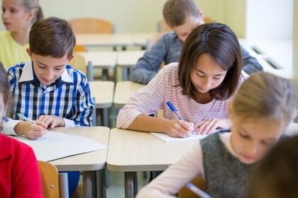 Kinder in der Schule notieren etwas auf Papier. 
