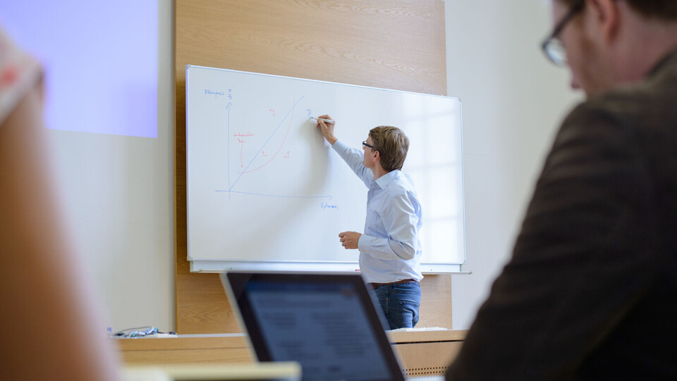 Doktorandenseminar Ein Mann schreibt etwas auf ein Whiteboard.