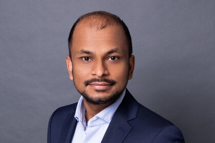 Santanu Kundu in einem hellblauen Hemd und dunklem Blazer vor einem grauen Fotohintergrund.