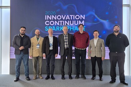 A group of six men in front of the logo for the Spark Event 26