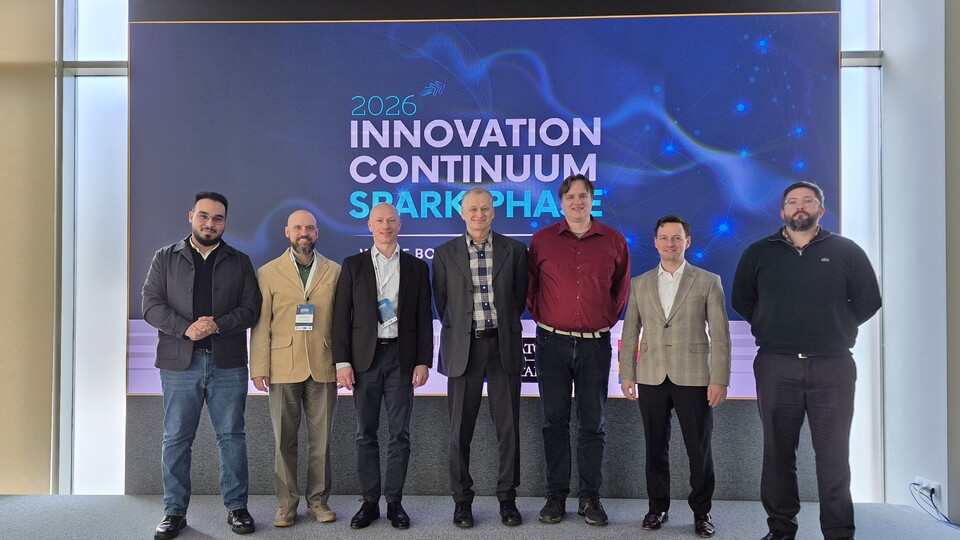 A group of six men in front of the logo for the Spark Event 26