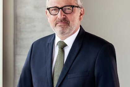 Porträt des Mannheimer Oberbürgermeisters Dr. Peter Kurz im Rahmen der Reihe "Almunus of the Month". Peter Kurz trägt eine schwarze Hornbrille, ein dunkelblaues Jacket und eine moosgrüne Krawatte. Sein kurzes Haar ist grau. Link: Instagram Post Alumnus of the Month