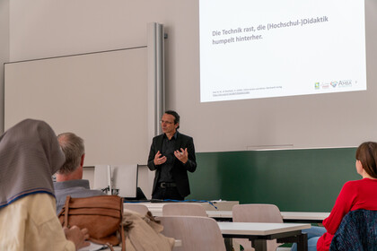 Vortragsszene bei der Veranstaltung ‚KI in der Hochschullehre‘ im Mannheimer Schloss: Ein Professor Ifenthaler spricht, Teilnehmende hören zu.