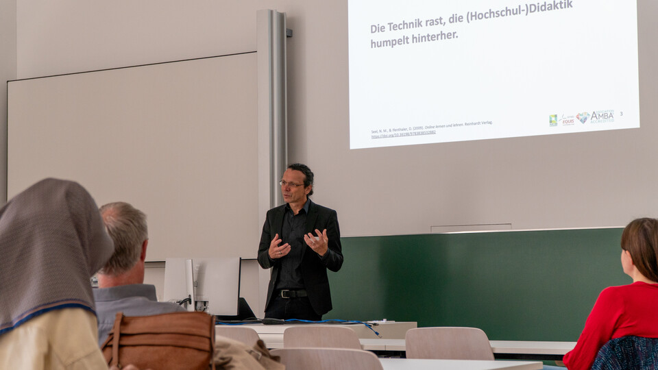 Vortragsszene bei der Veranstaltung ‚KI in der Hochschullehre‘ im Mannheimer Schloss: Ein Professor Ifenthaler spricht, Teilnehmende hören zu.