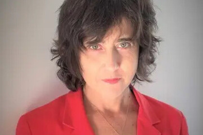Irena Kogan hat kurze, dunkle Haare und trägt einen roten Blazer.