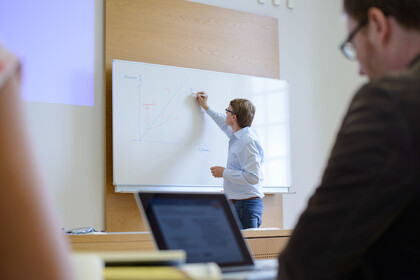 Ein Mann schreibt etwas auf ein Whiteboard.