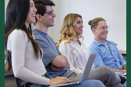 Vier Studierende (jeweils zwei weiblich und männlich gelesene) sitzen nebeneinander und blicken lächelnd in Richtung des rechten Bildrands. Die Person im Vordergrund hat einen Laptop auf dem Schoß. Das Bild ist dunkelgrün umrahmt, in der rechten oberen Ecke der Hashtag #scientistsforfuture.