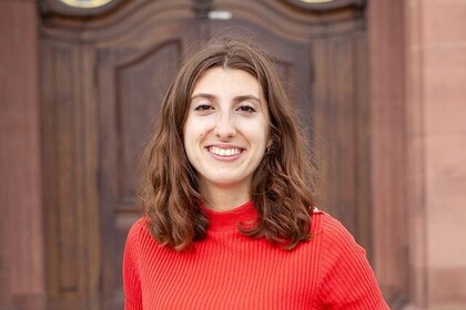 Léa Beringuer hat mittellange braune Haare. Sie trägt ein rotes T-Shirt und lächelt in die Kamera.