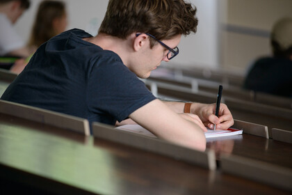 Ein Student schreibt etwas auf seinen Block.
