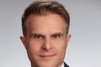Portrait von Florian Stahl. Er trägt einen schwarzen Blazer, sowie eine schwarze Krawatte und ein weißes Hemd. 