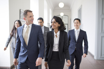 Personen in Business Kleidung laufen den Flur entlang