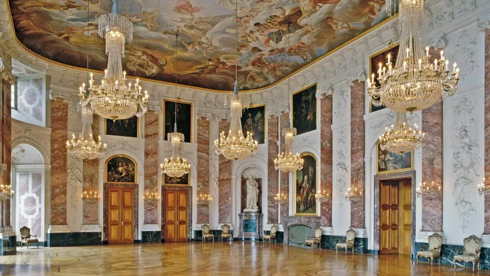 Prunkvoller Barocksaal im Mannheimer Schloss mit Kristalllüstern, Deckenfresken und vergoldeten Türen.