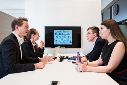 Studierende sitzen um Tisch mit Bildschirm