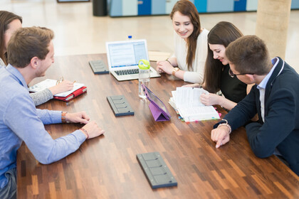 Studierende mit Lernmaterialien sitzen um Tisch
