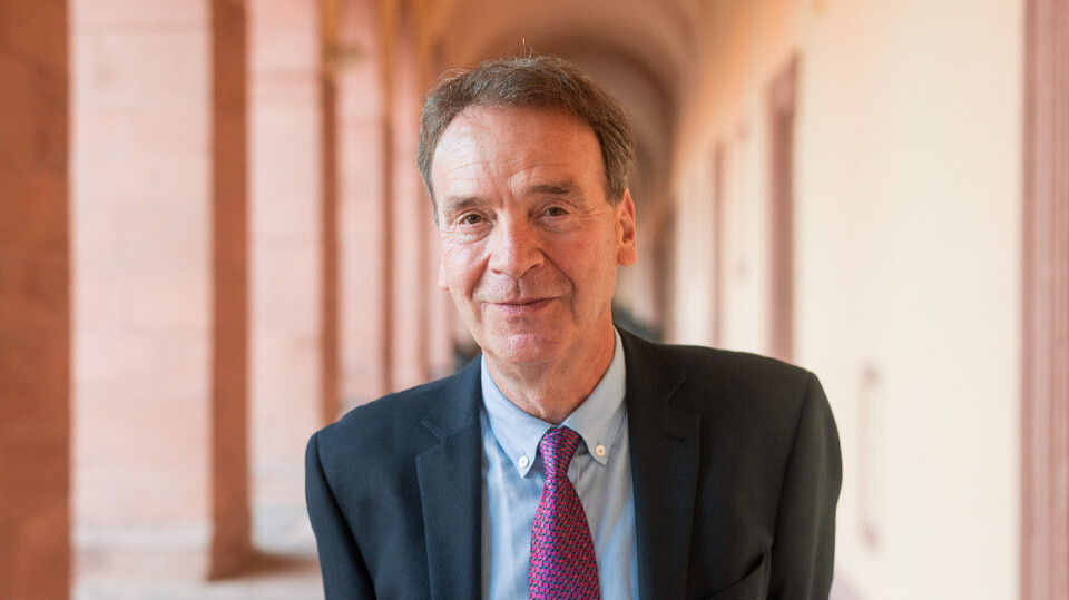 Prof. Reichelstein has short hair and wears a suit and tie.