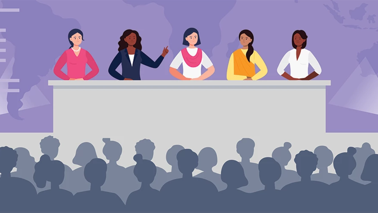 Bild von fünf Frauen verschiedner Ethnien auf Bühne hinter Rednerpult