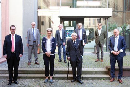 Mehrere Personen in Anzügen stehen in eiem Innenhof der Universität Mannheim. 