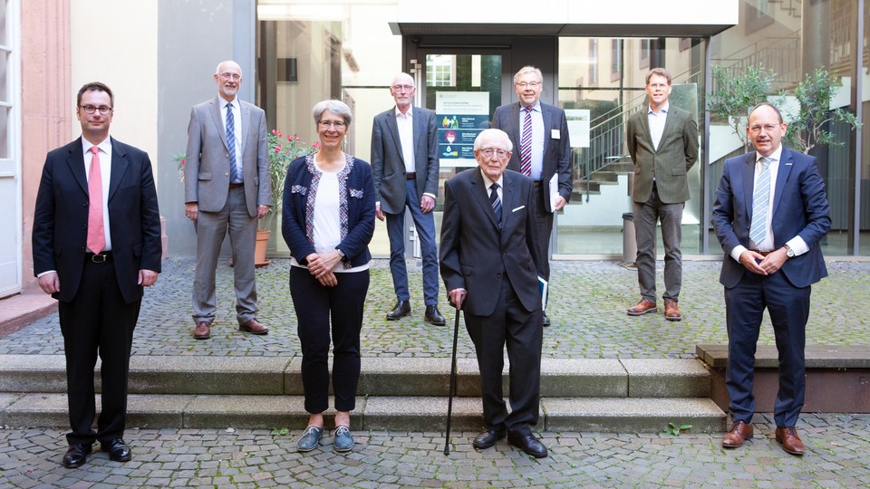Mehrere Personen in Anzügen stehen in eiem Innenhof der Universität Mannheim.