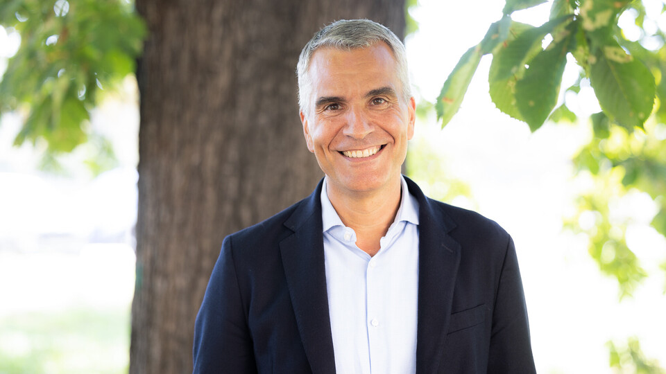 Prof. Dr. Thomas Fetzer. Breit lächelnd steht er vor einem Baum, dabei trägt er ein dunkles Jackett.