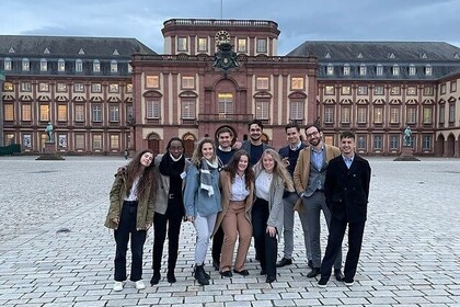 Foto einer Gruppe auf dem Ehrenhof. Im Hintergrund ist der Mittelbau der Universität Mannheim zu sehen.