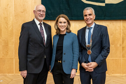 Prof. Dr. Thomas Puhl (links), Ministerin Petra Olschowski und Prof. Dr. Thomas Fetzer (rechts) bei der Rektoratsübergabe, während sie lächelnd nebeneinander stehen.
