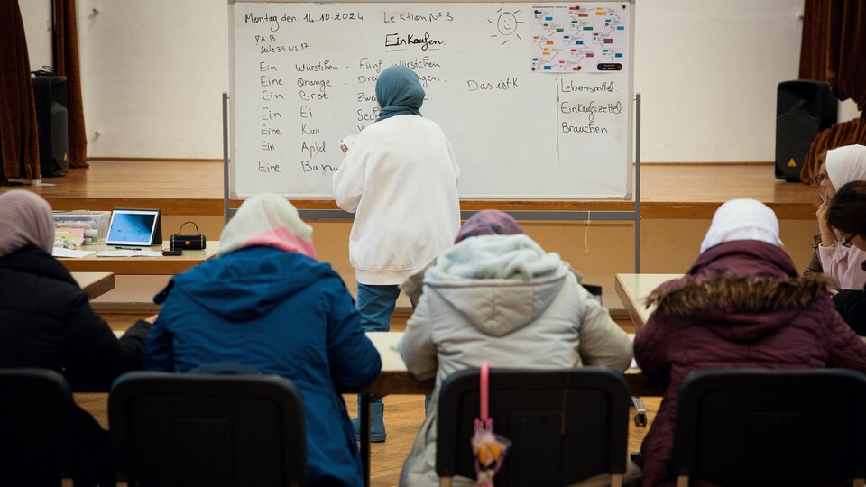 Schulklasse bestehend aus Frauen und an der Tafel steht eine Lehrerin