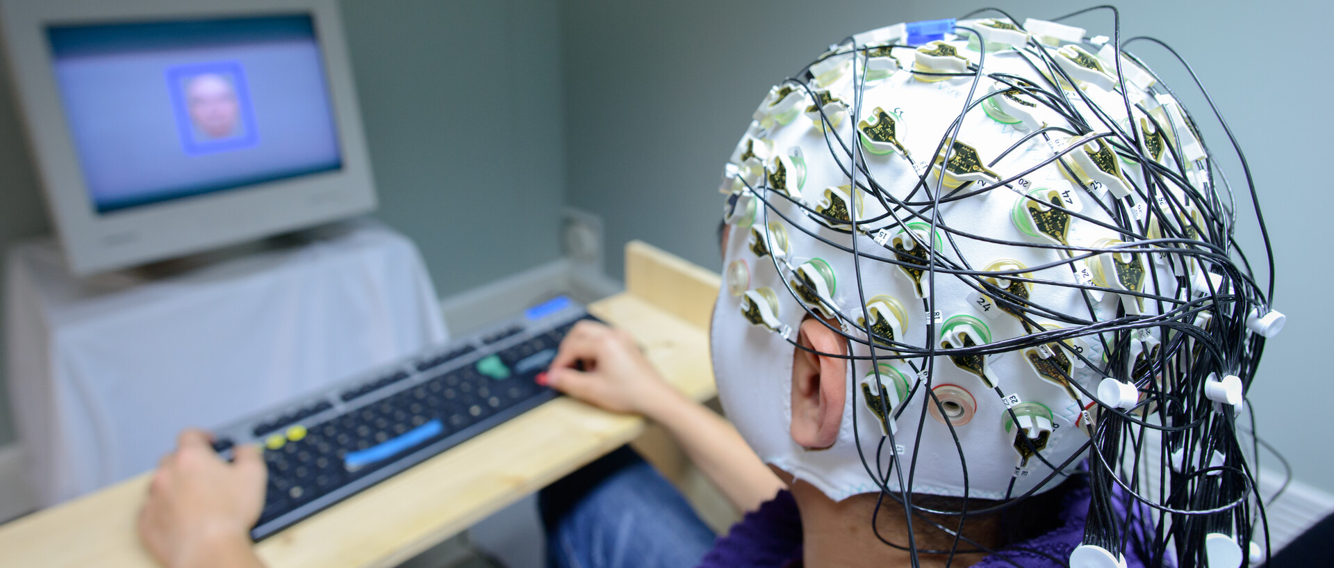 Menschen sitzt vor einem Computer und trägt eine Instrument zur Messung von Hirnströmen