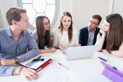 Studierende mit Laptops sitzen um einen Tisch