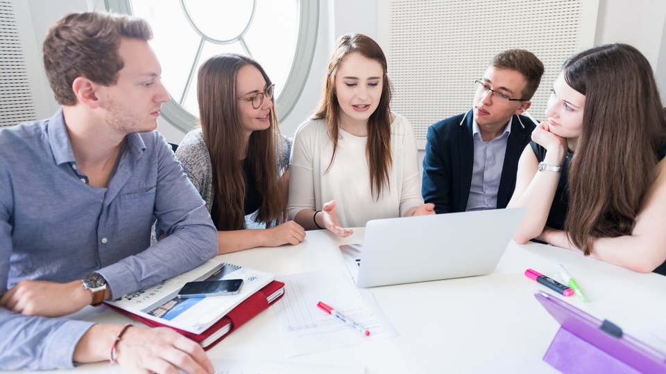 Studierende mit Laptops sitzen um einen Tisch