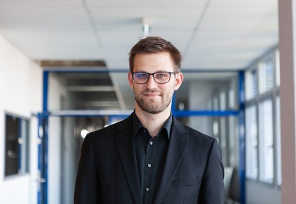 Dr. Stefan Janke hat kurze braune Haare, einen Bart und eine Brille. Er trägt ein schwarzes Jacket und ein schwarzes Hemd.