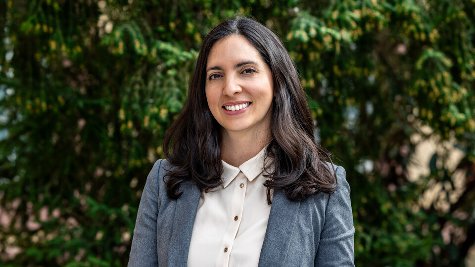 Karla Funes. Karla Funes lächelt und trägt einen blauen Blazer sowie eine weiße Bluse.